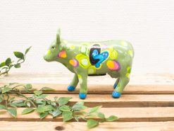 Whimsical green ceramic cow figurine with colorful polka dots for cheerful decor.