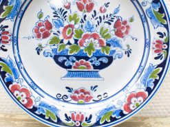 Stunning vintage porcelain plate featuring vibrant floral motif and classic urn design.