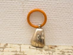 Vintage orange-brown keychain with a charming silver bell, perfect for nostalgic collectors.