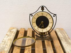 Antique-style vintage table clock with magnifying glass, elegant brass and iron design.