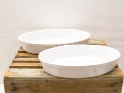 Elegant white serving dishes on rustic wooden surface for stylish dining presentations.