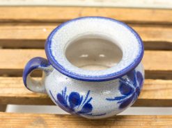 Handmade beige ceramic flower pot with blue floral design and handle for easy lifting.