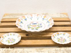 Charming vintage ceramic bowl set with floral designs on a rustic wooden table.