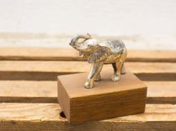 Intricate silver elephant sculpture on wooden base, symbolizing luck and strength for elegant decor.