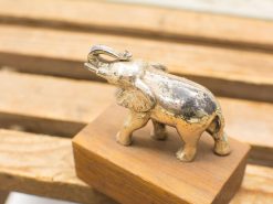 Playful metal elephant sculpture on a wooden base, reflecting charm and positivity.