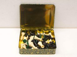 Vintage chess set in ornate metal box with elegant gold interior and mixed pieces.