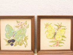 Elegant cross-stitched butterflies in antique wooden frames celebrating natures beauty and craftsmanship.