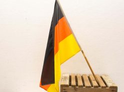 Vintage German flag displayed on rustic crate, ideal for patriotic decor and collectors.