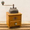 Vintage wooden coffee grinder in yellow and blue, showcasing charm and history.