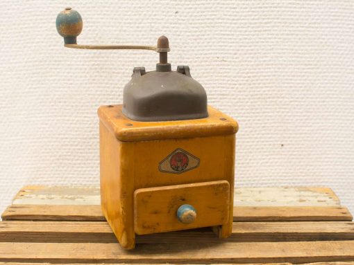 Vintage wooden coffee grinder in yellow and blue, showcasing charm and history.