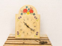 Charming vintage wooden clock with floral design and Roman numerals, perfect for rustic decor.