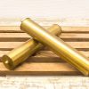 Elegant vintage brass tubes with knobs on a rustic wooden surface, perfect for collectors.