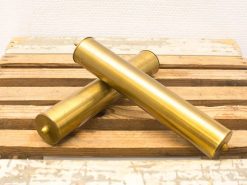 Elegant vintage brass tubes with knobs on a rustic wooden surface, perfect for collectors.