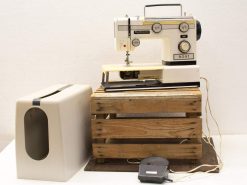 Vintage Diplomat sewing machine on rustic wooden pallet, featuring retro design and protective cover.