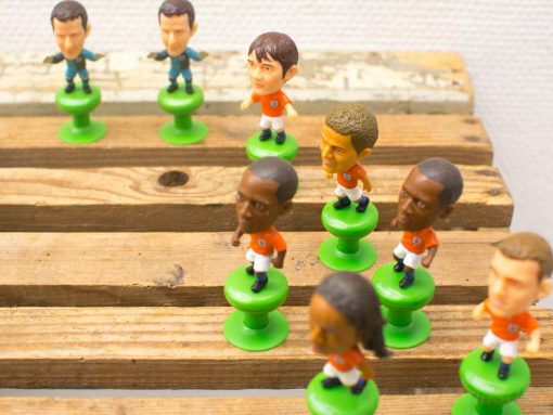 Vintage soccer figurines in orange jerseys for nostalgic tabletop gaming fun.