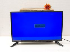 Sleek modern TV with wooden plank and vibrant artificial flower decor.