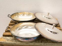 Elegant stainless steel pan set with lids on rustic wood, perfect for stylish cooking.