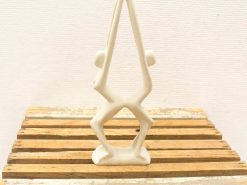 Abstract sculpture of two figures symbolizing unity and support, featuring a sleek design on wood.