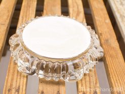 Elegant vintage glass dish with scalloped edges on rustic wooden surface. Perfect for decor or serving.