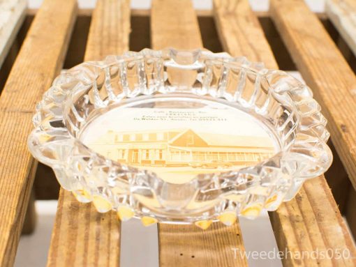 Elegant vintage glass ashtray with historic building illustration on rustic wooden surface.