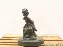 Charming bronze statue of a girl seated on a rock, perfect for any decor.