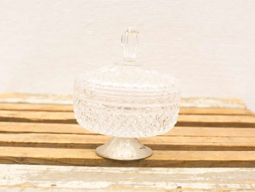 Elegant crystal jar with lid, featuring intricate patterns and rustic wooden backdrop.