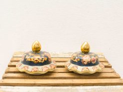 Elegant blue and gold decorative lids with floral patterns on a rustic wooden surface.