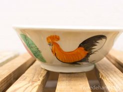 Colorful ceramic bowl featuring a vibrant rooster and green foliage design, perfect for decor or dining.