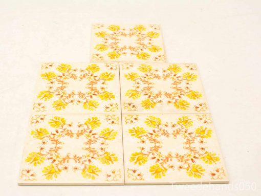 Intricate decorative ceramic tiles featuring floral designs in warm yellow and brown tones.