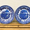 Intricate 19th-century blue and white decorative plates showcasing pastoral scenes and floral designs.