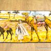 Desert life tapestry featuring a camel, child on horse, and vibrant palm trees.