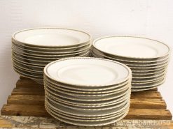 Elegant stacked china plates with gold rims on a rustic wooden surface.