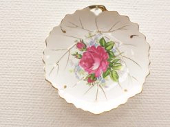 Elegant vintage porcelain plate with pink rose, green leaves, and gold detailing.