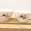 Elegant porcelain bowls with vibrant rose patterns on a rustic wooden surface.