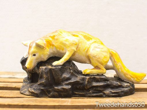 Inquisitive fox figurine on textured rock, showcasing vibrant colors and intricate craftsmanship.