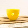 Bright yellow ceramic bowl with unique cut-outs, perfect for decor or candles.