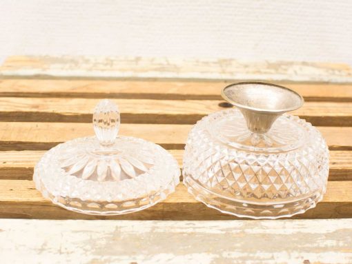 Elegant glass containers with decorative lids on a rustic wooden background.