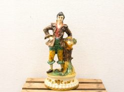 Charming porcelain figurine of a youthful boy in vibrant colors celebrating rustic life.