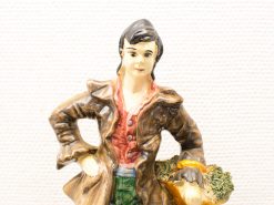 Charming vintage porcelain figurine of a young farmer with a basket emphasizing rural life.