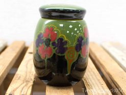 Vibrant green ceramic jar with floral patterns and a glossy black lid, perfect for decor.