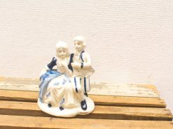 Charming porcelain figurine of playful children in traditional attire, perfect for collectors.