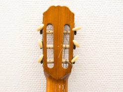 Elegant classical guitar headstock with six tuners, showcasing fine craftsmanship and natural wood grain.