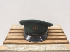 Elegant green military cap with crown emblem on rustic wooden base, showcasing craftsmanship and tradition.