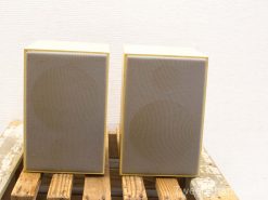 Sleek cream speakers on rustic wood, perfect for style and sound in any decor.