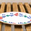 Vibrant vintage oval platter with colorful floral designs on rustic wooden surface.