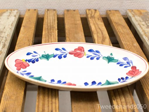 Vibrant vintage oval platter with colorful floral designs on rustic wooden surface.