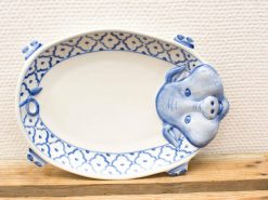 Vintage oval plate with blue floral design and playful pig head details.