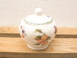 Elegant porcelain container adorned with vibrant painted fruits and butterflies on a white background.