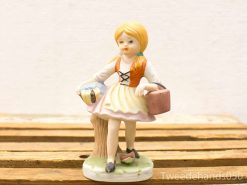 Charming porcelain figurine of a playful girl with braids, dressed in vintage style.