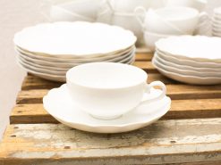 Elegant white porcelain teacup and saucer on a rustic wooden table, perfect for gatherings.